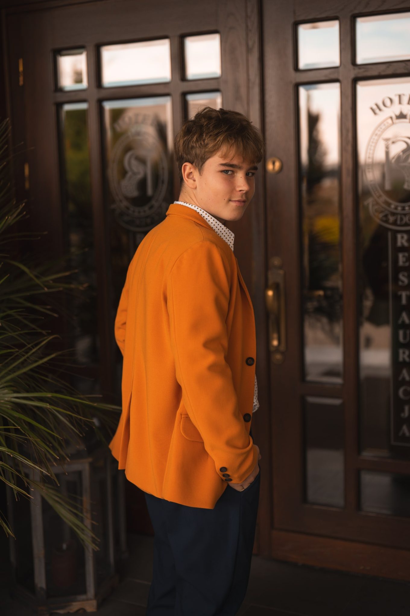 Marynarka chłopięca pomarańczowa Młody model w pomarańczowej marynarce, pokazuje tył marynarki